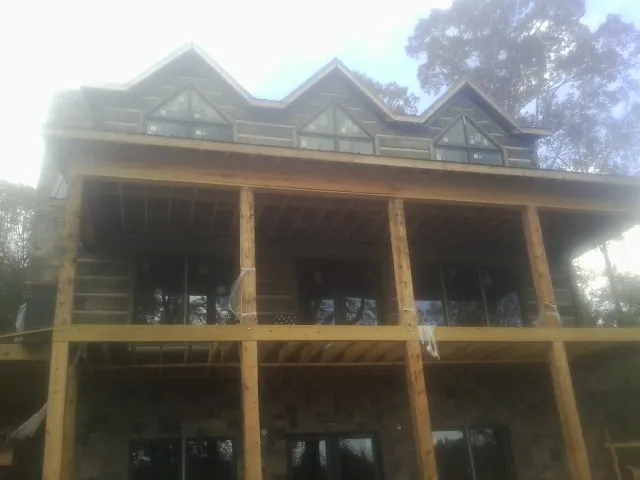 Dormers and porch framing on a large log home under construction — Roof Coating work by our crew in Anamosa