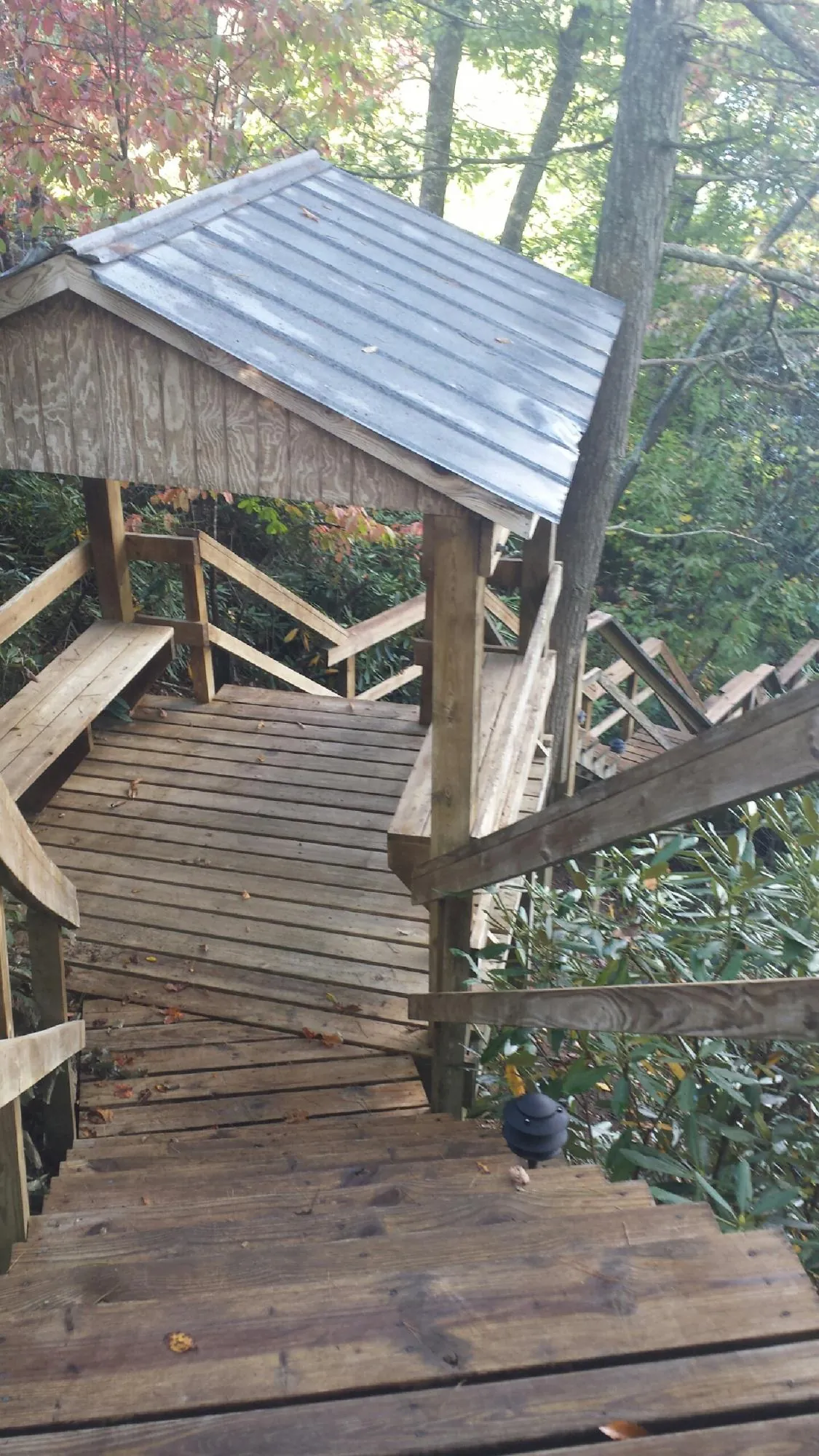 Metal roofed shelter over wooden steps on a wooded walkway — Skylight Repair & Installation work by our crew in Anamosa