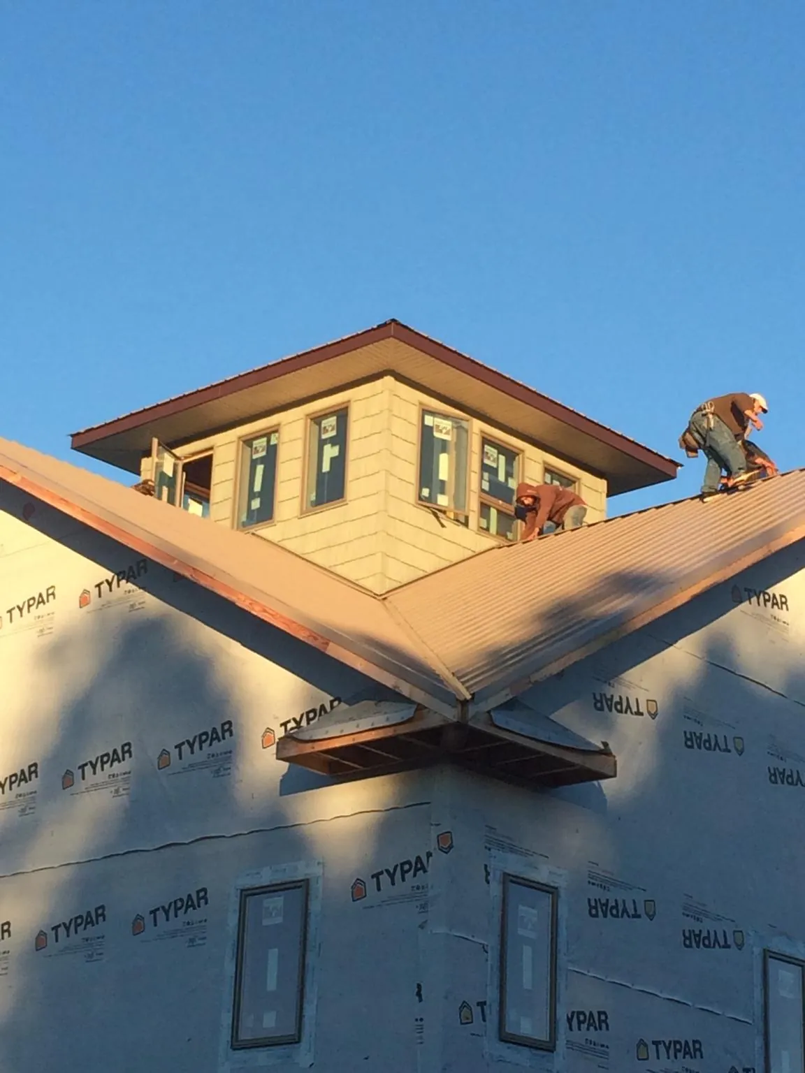 Roofers working around a rooftop cupola on a new metal roof at sunset — Roof Waterproofing in Anamosa by Roofing Brothers